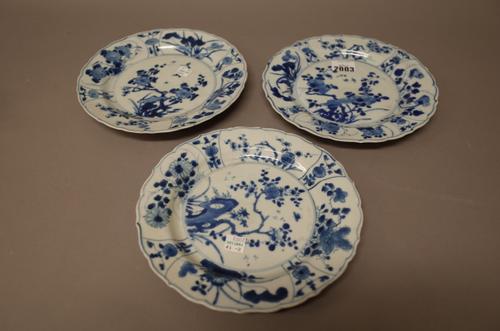 Three Chinese blue and white plates, 18th century, each painted in the centre with branches of prunus, beneath a panelled border enclosing flowers, ba