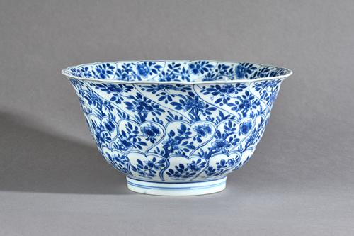 A Chinese blue and white bowl, Kangxi, the exterior moulded with shaped panels enclosing flowers, the interior painted with a panelof flowers issuing