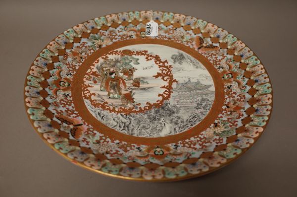 A  Japanese Kutani dish, Meiji period, painted en grisaille and enamels with a pavilion and trees and reserving a figurative panel inside an iron-red