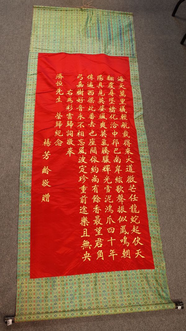 A Chinese hanging embroidered scroll, with gilt calligraphy on a red ground, 152cm. by 68cm.