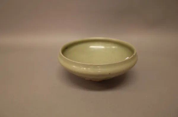 A Chinese celadon bowl, Song dynasty, the exterior carved with lappets, the interior with swirls around a circular panel, 16cm. diameter; also a Canto