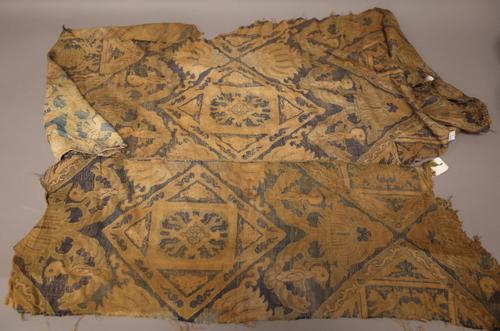 Two Chinese silk fragments, possibly Tang dynasty, each worked with a repeated design of birds and foliate medallions against a dark blue ground, (a.f