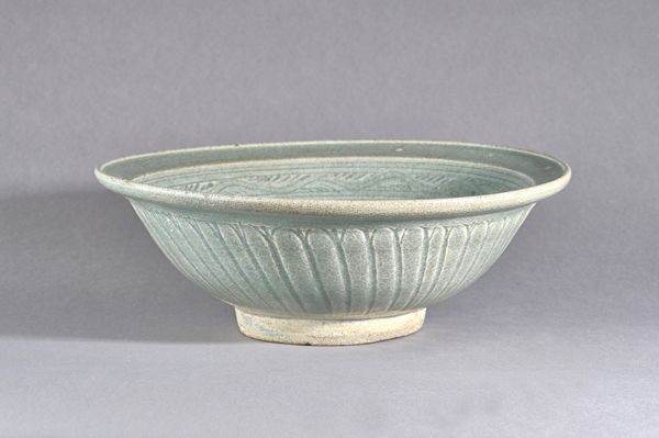 A Thai celadon glazed deep bowl, Sawankhalok, 14th-16th century, the interior incised with a horizontal band of waves, the exterior incised with flute
