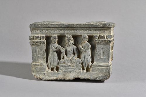 A Gandhara grey schist fragment from a statue base, 3rd/4th century, AD, depicting Buddha Maitreya flanked by devotees within a niche supported by Cor
