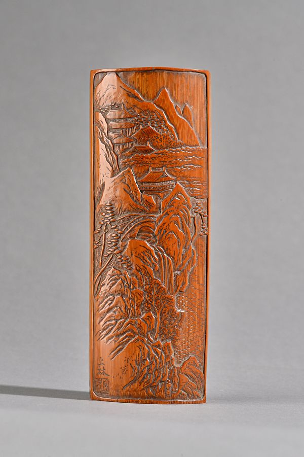 A Chinese bamboo wrist rest, possibly 18th century, deep carved with pavilions and a bridge in a mountainous landscape, signed, 16.5cm.length. Illustr