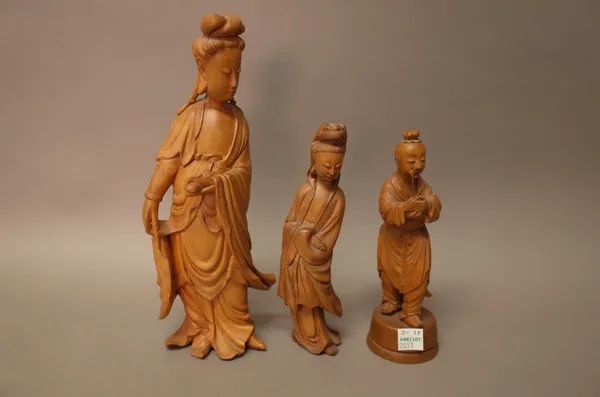 A Chinese boxwood figure of Guanyin, standing in long robes holding a scroll in her left hand, 24cm. high; also a smaller boxwood figure of Guanyin, 1