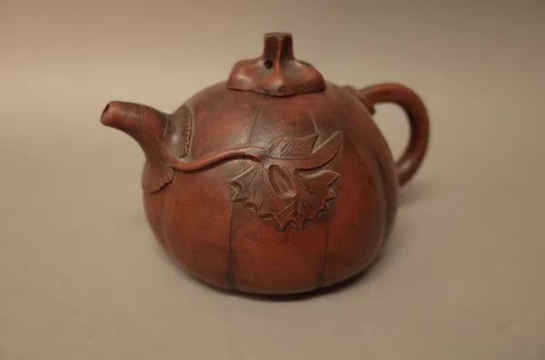 A Chinese Yixing teapot and cover, of pumpkin form with two leafy branches extending from the short spout and loop handle, 10cm. high.