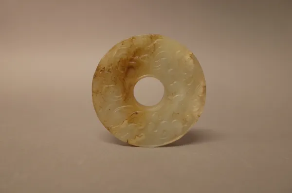 A Chinese jade bi disc, possibly Yuan dynasty, each side carved with two sinuous chilong, the stone of greyish tone with russet inclusions, 6.5cm. dia