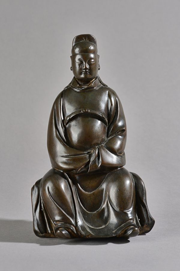 A Chinese bronze figure of a scholar, possibly 18th century, cast in seated pose with serene expression, 25cm. high, later wood block stand, (2). Illu