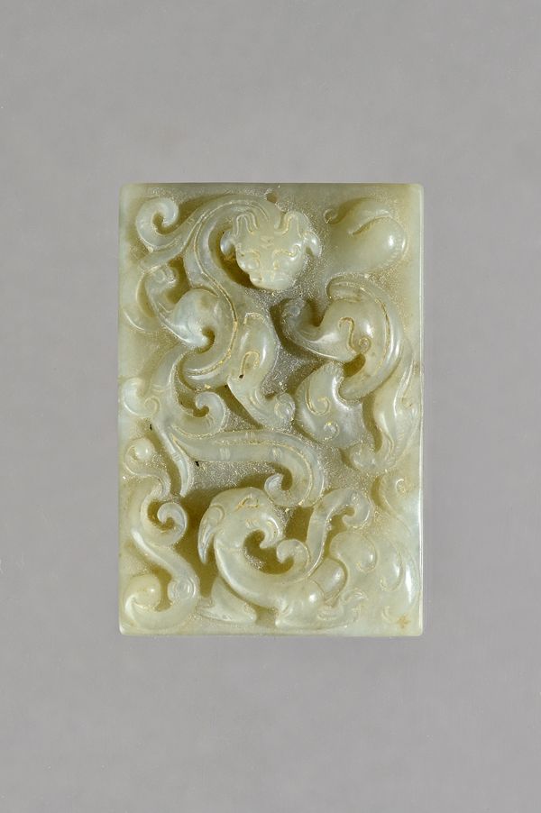 A Chinese celadon jade rectangular pendant, possibly Yuan dynasty, carved in high relief with a chilong and phoenix, 5.75cm. high. Illustrated