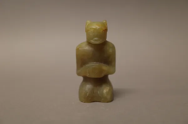 A small Chinese jade figure, possibly Han dynasty, carved in kneeling pose, the stone of celadon tone with russet inclusions, 5.5cm. high.