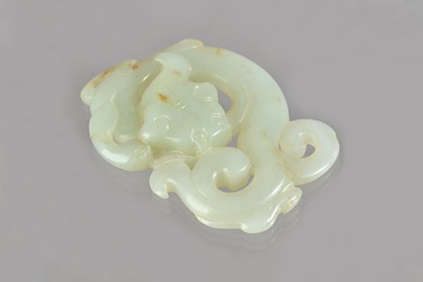 A Chinese celadon jade plaque, probably Song dynasty, carved and pierced as a chilong, the stone of pale celadon tone, 7cm. wide. Illustrated
