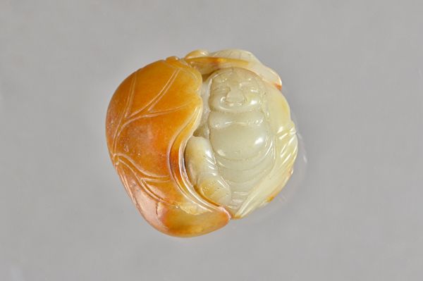 A Chinese celadon and russet jade pendant, probably Ming dynasty, carved as a smiling Liu Hai sat beside a large lotus leaf, the reverse carved with h