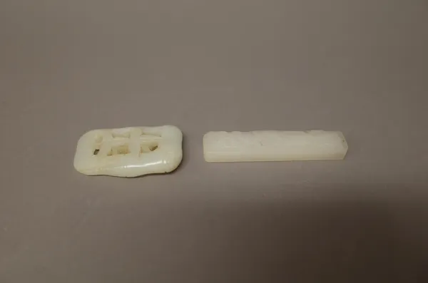 A Chinese white jade rectangular pendant, carved on one side with a tree trunk, 7cm. high; also a white jade bamboo pendant, 5cm. high, (2).