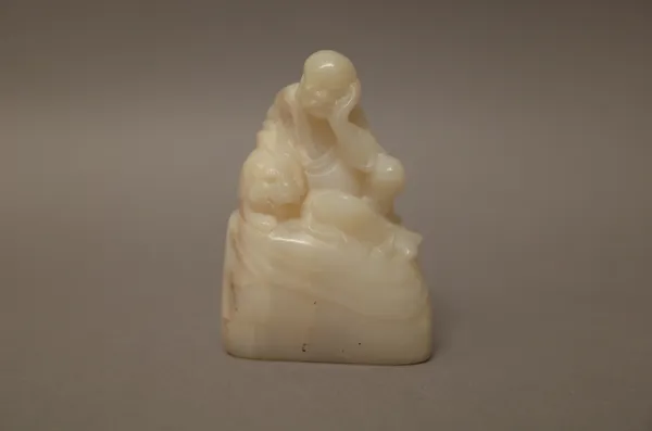 A Chinese white soapstone group, probably 19th century, carved as a luohan seated with one arm resting on a recumbent tiger at his side, incised chara