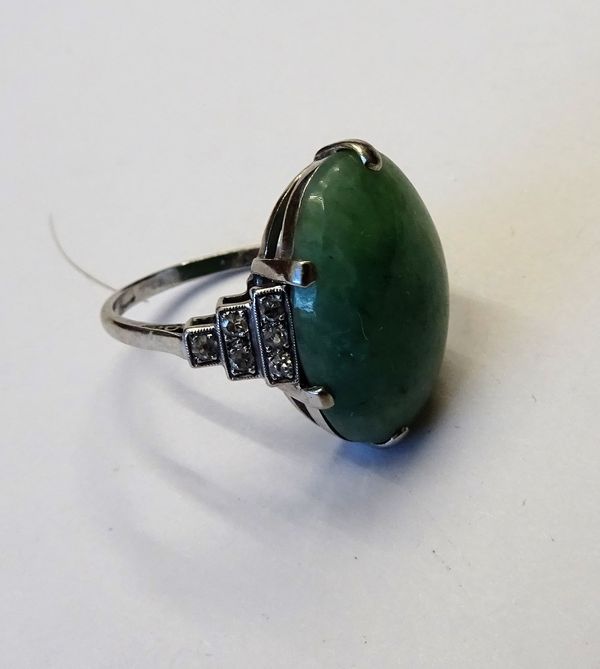 A platinum, jade and diamond ring, claw set with the oval jade cabochon between diamond set stepped shoulders in the Art Deco taste, detailed PLAT, ri