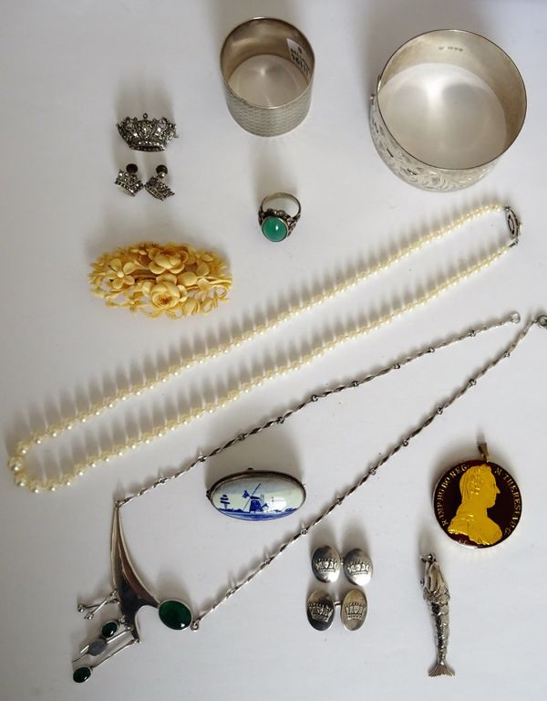 A single row necklace of graduated cultured pearls, on a silver clasp, a carved ivory shaped oval brooch, in a floral design, a Delft pottery brooch,