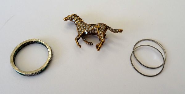 An emerald and diamond set eternity ring (damaged), ring size M and a gold and diamond set brooch, designed as a running horse, (2).