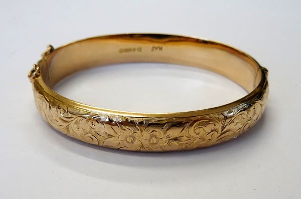 A 9ct gold oval hinged bangle, the front with floral, foliate and scroll engraved decoration, on a snap clasp, Chester 1918, gross weight 10.8 gms.