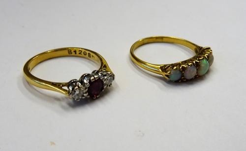 An 18ct gold ring, mounted with a row of five graduated opals, ring size N and a half and an 18ct gold, ruby and diamond three stone ring, claw set wi