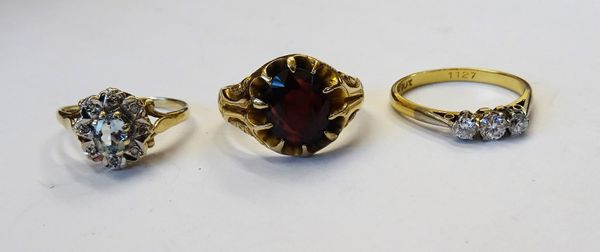 A Victorian 9ct gold ring, claw set with an oval cut garnet, between decorated shoulders, Chester 1900, a gold and platinum, diamond set three stone r