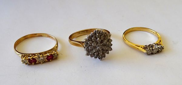 A 9ct gold and diamond set hexagonal cluster ring, an 18ct gold and diamond set three stone ring, claw set with a row of circular cut diamonds and a 1