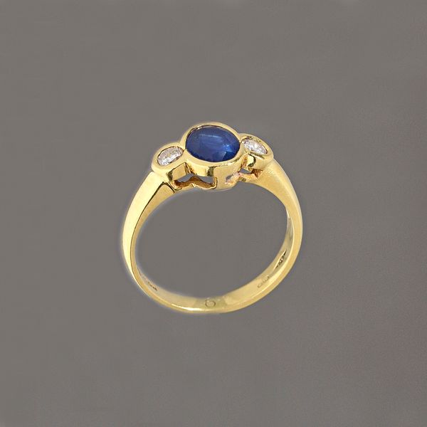 An 18ct gold, sapphire and diamond three stone ring, collet set with an oval cut sapphire between two circular cut diamonds, detailed 750, ring size N