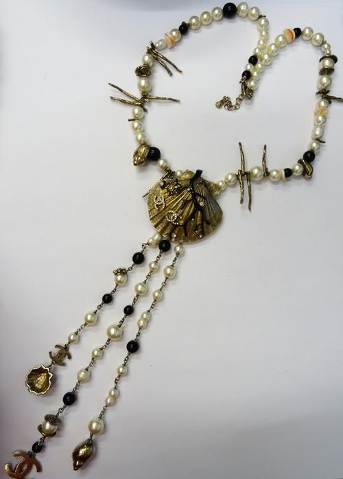 A Sautoir Chanel, Cruise Collection, 2005, designed as a gilt metal seashell pendant with applied black enamel and paste set imitation coral, otherwis