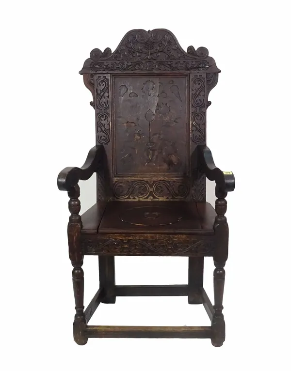 An 18th century and later oak open arm commode chair with carved back.