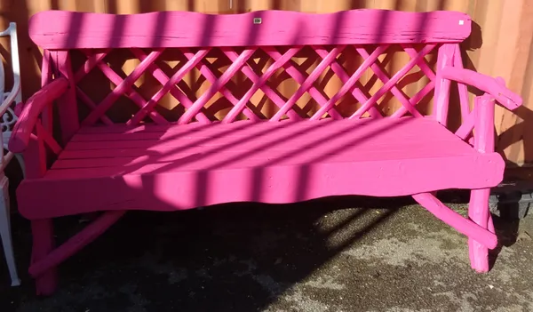 A neon pink painted hardwood garden bench of naturalistic form, 178cm wide.