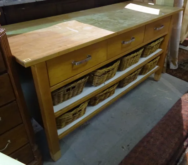 A 20th century beech kitchen unit with three drawers over two shelves with eight wicker baskets, 176cm wide x 90cm high.