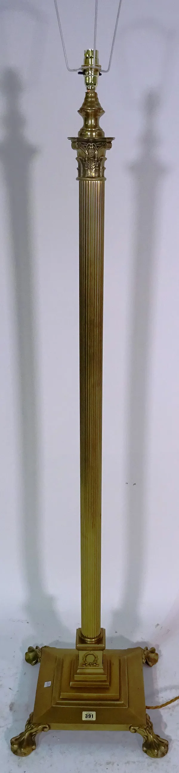A 20th century brass standard lamp on Corinthian column form on paw feet, 129cm high excluding fitments.