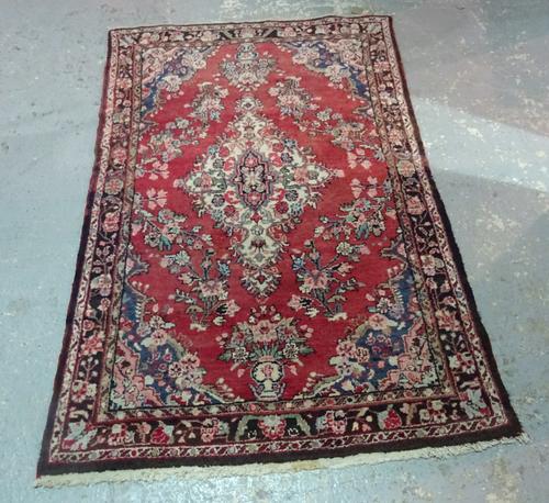 A Persian tribal rug in a Tabriz design, claret red field with stepped white medallion and black main border, 207cm x 128cm.