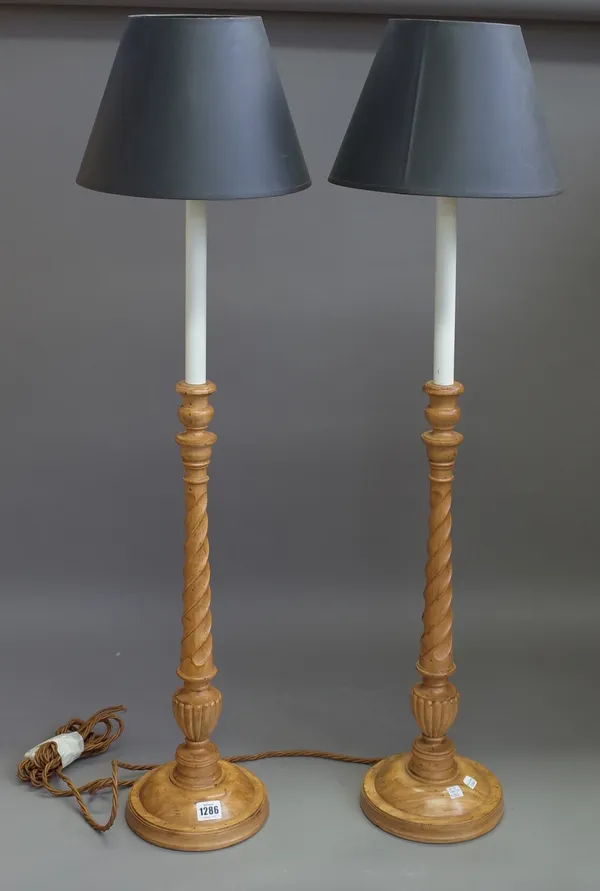 A pair of fruitwood carved table lamps with barley twist stems and a circular foot with black shades, 101cm high overall. (2)