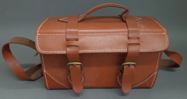 A heavy leather and brass mounted travel bag with buckle and strap fastening and adjustable shoulder strap, 40cm x 21cm x 15cm