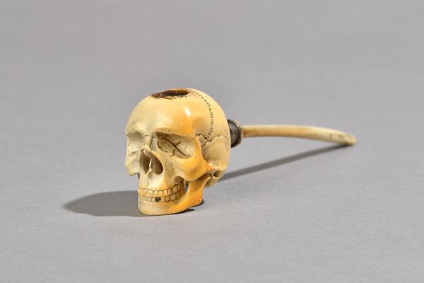 A Meerschaum pipe 19th century, the bowl carved as a human skull with animal horn mouthpiece, bowl 4cm high, with case.  Illustrated £10 1321