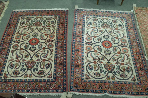 A pair of Isfahan rugs, Persian, each with an ivory field, a central rosette and thorned floral vines, a madder palmette and floral spray border, 145c