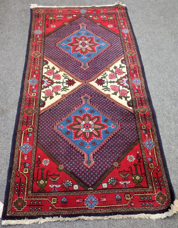 A Sonchor rug, Persian, the field with two indigo diamonds centred by a large flowerhead, floral sprays and vases to support areas, a madder vine and