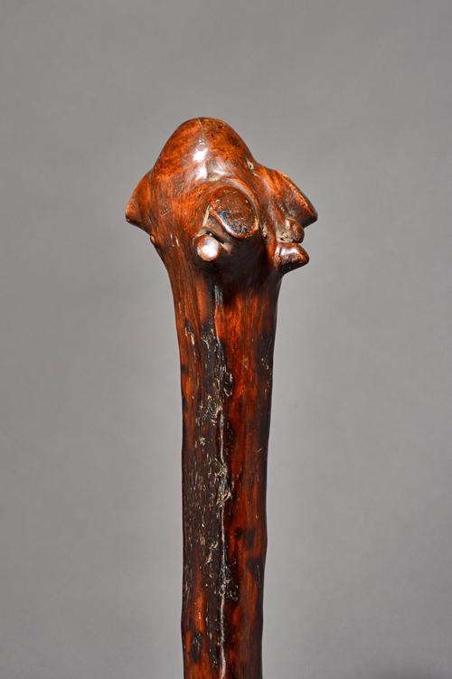A New Caledonian hardwood war club, the head of naturalistic bulbous root form, with tapering shaft and plain raised grip, 67cm. Illustrated