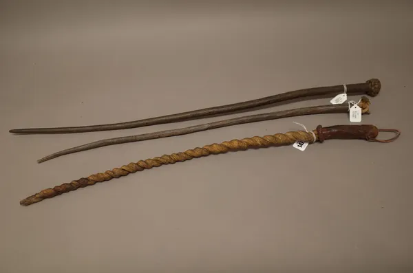 An African leather or sinew whip of spiral twist form, with a leather grip (69cm) and two further African leather whips, with knotted handles, (3).