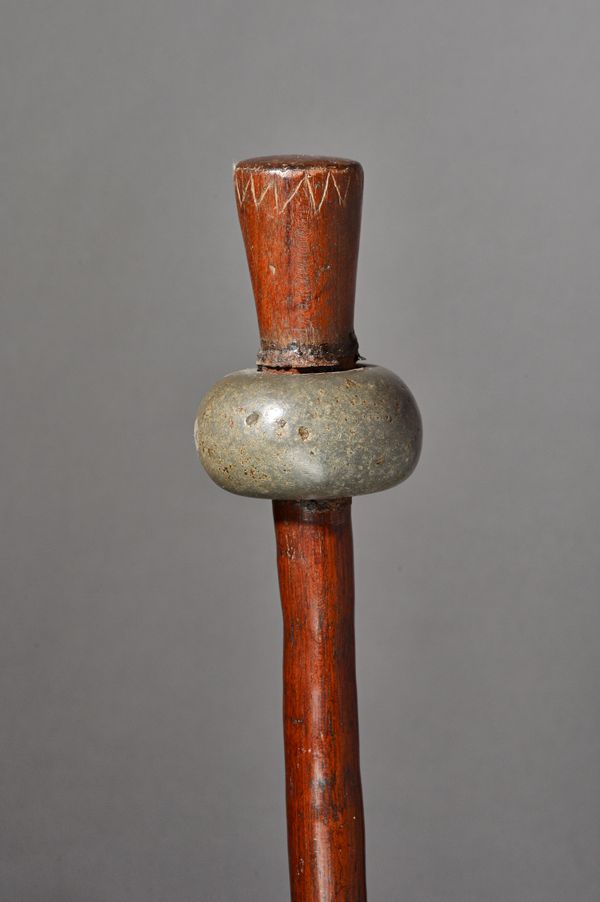 A New Britain mace club, the ovoid stone head on a carved tapering cylindrical shaft, 135cm. Illustrated
