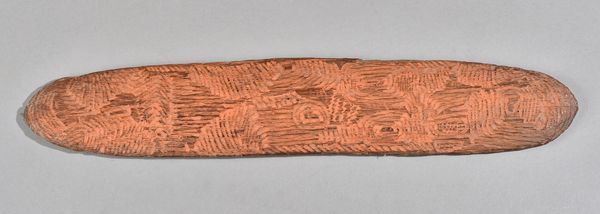 An Australian Aboriginal Tjuringa, carved geometric pattern, red painted detail, 40.5cm. Illustrated