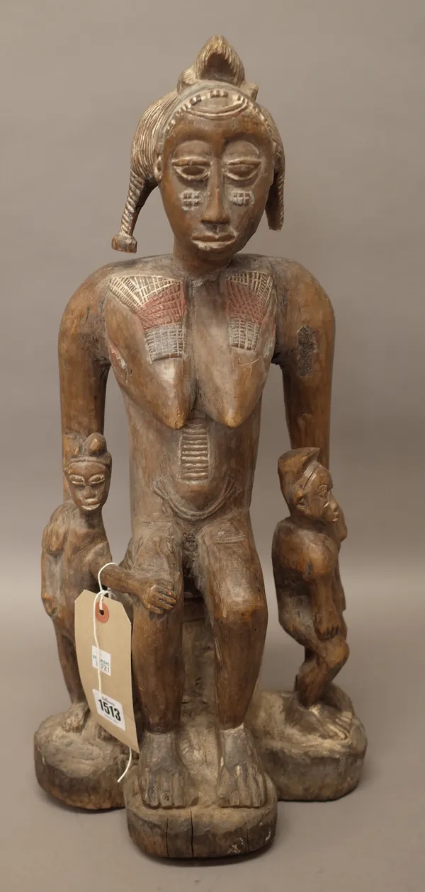 A Baule tribal wooden maternity figure group, the carved mother seated flanked by her children with polychrome painted detail, 51cm high. Illustrated