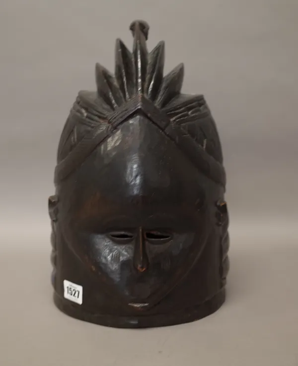 A West African Mende tribe 'Sowei' carved wooden helmet mask, black patina with ridged coiffure, 36cm high.