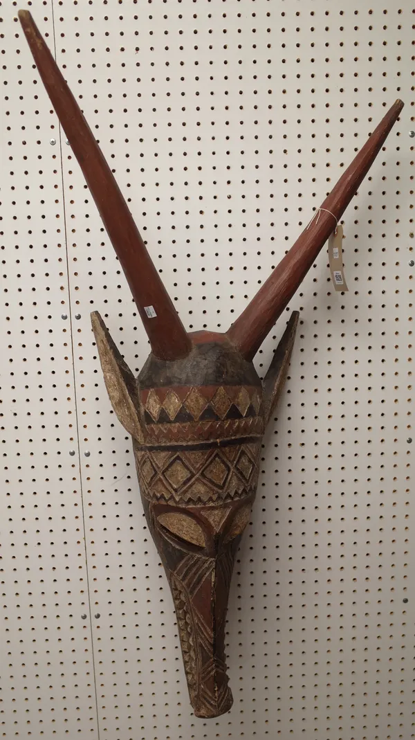 An African polychrome painted carved wood Zoomorphic tribal mask, with long horns and geometric decoration, 109cm.