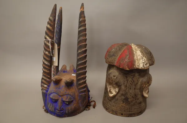 An African tribal helmet mask, polychrome painted carved wood with crested surmount, 33cm high and another African helmet mask, blue pigment, with fou