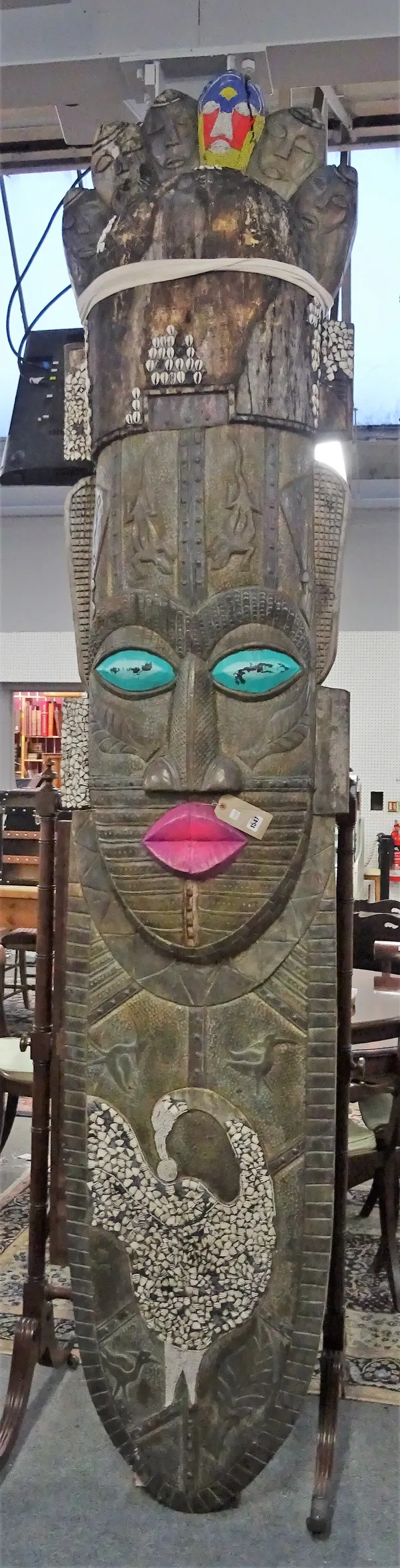 A South Sea Island hardwood Totem mask of large proportions, overlaid with embossed metal and embellished with beads and shells, 300cm high.