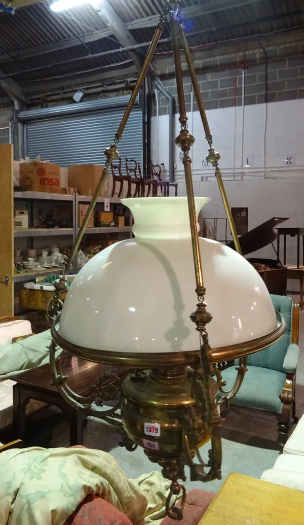 A Victorian style gilt metal hanging oil lamp (converted to electricity), the circular foliate cast body and opaque glass shade suspended by three lin