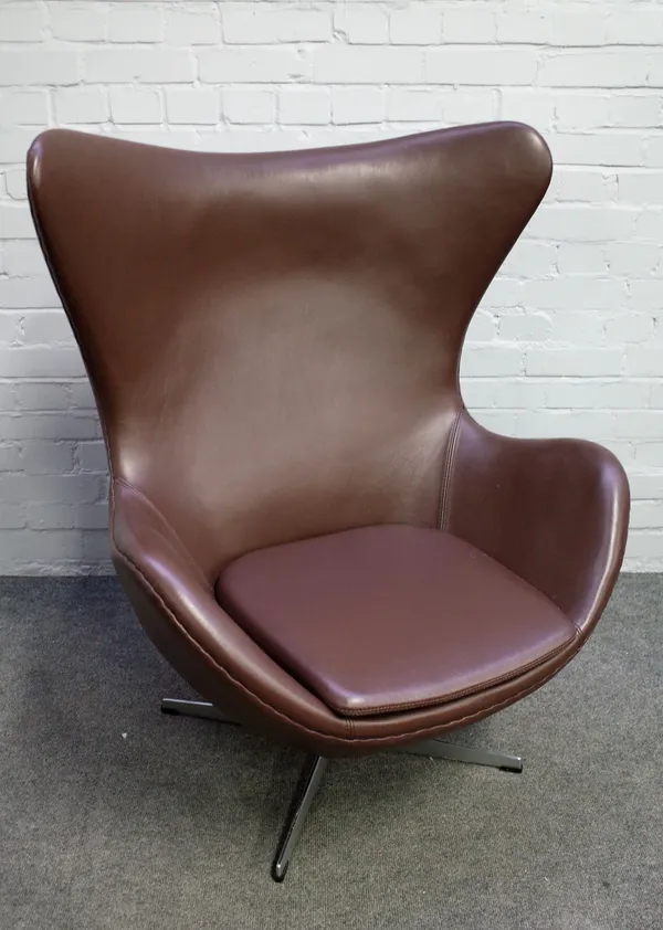 After Arne Jacobsen; an egg chair in brown leather on polished steel four point base, 87cm wide x 105cm high.