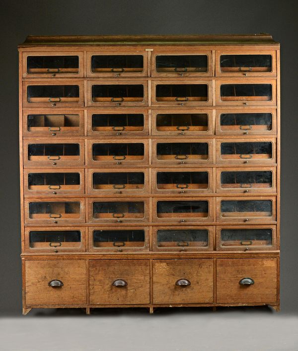 JAMES BOOTLE LTD, COMPLETE SHOP FITTERS, EASTBOURNE; a mid-20th century oak haberdashery cabinet, with four rows of seven drawers enclosing pull-out t